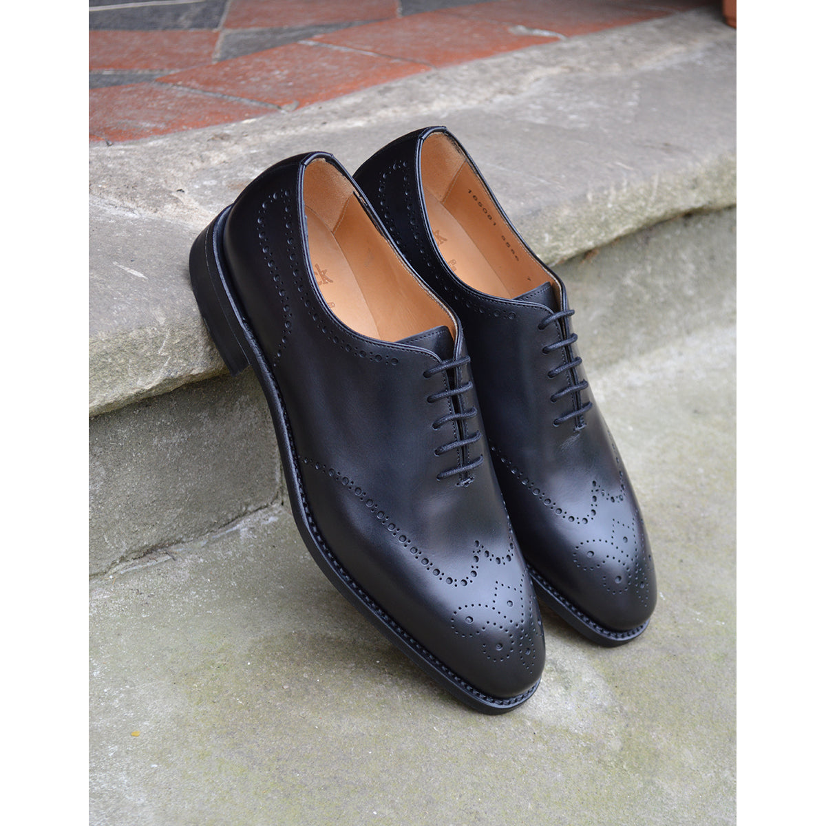A black wholecut Oxford brogue shoe with a brogue pattern on the upper, a lace-up closure, and a goodyear welted leather sole.