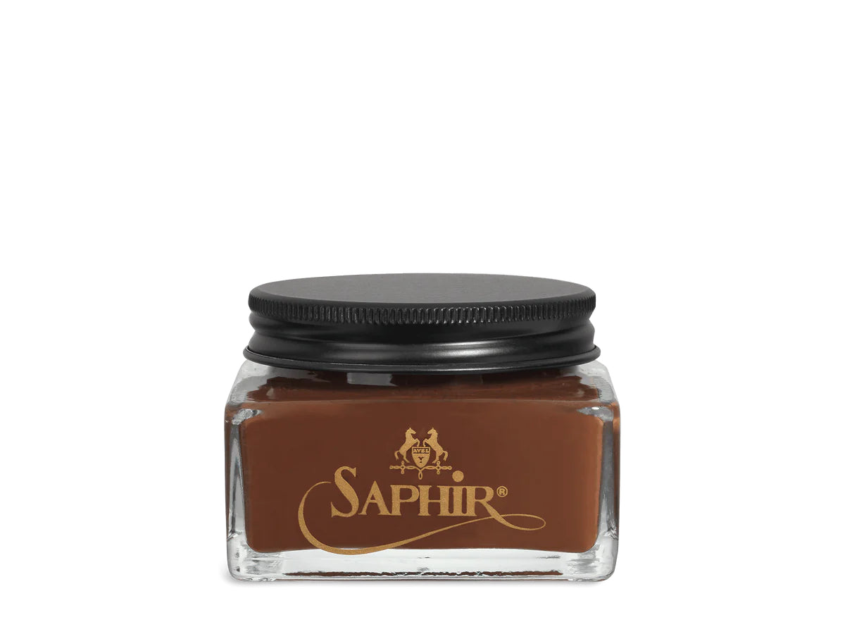 A glass jar with a black lid labeled 'SAPHIR' containing cream shoe polish.