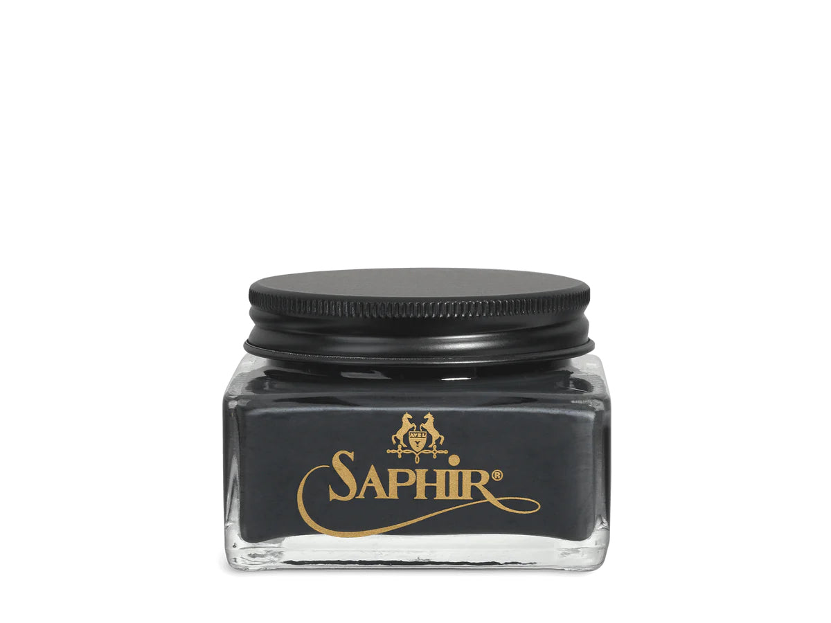 A glass jar with a black lid labeled 'SAPHIR' containing cream shoe polish.
