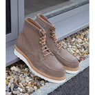 A grey and tan suede apron boot with lace-up closure, featuring a white sole and a natural welt.