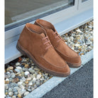 A brown Berwick 1707 5432 Apron Boot with lace-up closure, handcrafted from reverse kudu suede, featuring moccasin stitching and a crepe rubber sole.