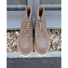 A grey and tan suede apron boot with lace-up closure, featuring a white sole and a natural welt.