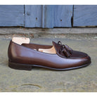 A Berwick 1 707 dark brown leather Belgian loafer with a braided leather bow tie and tassel adornment.