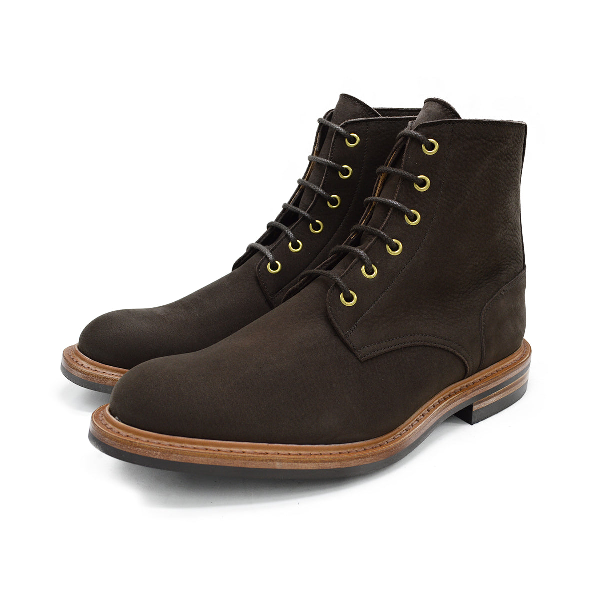 A dark brown Trickers Bernwood service boot made of Hydro Nubuck with a Dainite sole, featuring brass eyelets and a cream Barbour welt.