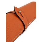 A Saphir Medaille D'Or rolled-up orange leather shoeshine mat with a nickel stud on the exterior.