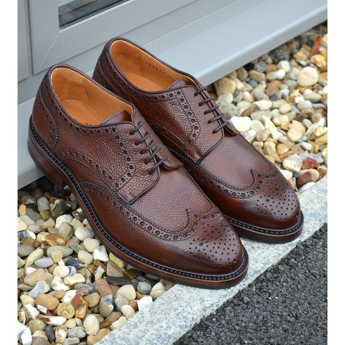 A Berwick 1707 brown brogue derby shoe with a round toe shape and lace-up closure. It features a grainy texture and brogue detailing & Dainite soles