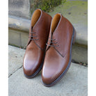 A dark brown grain leather chukka boot with a round toe and goodyear welted dainite rubber sole.