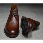 A dark brown grain leather chukka boot with a round toe and goodyear welted dainite rubber sole.
