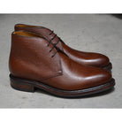 A dark brown grain leather chukka boot with a round toe and goodyear welted dainite rubber sole.