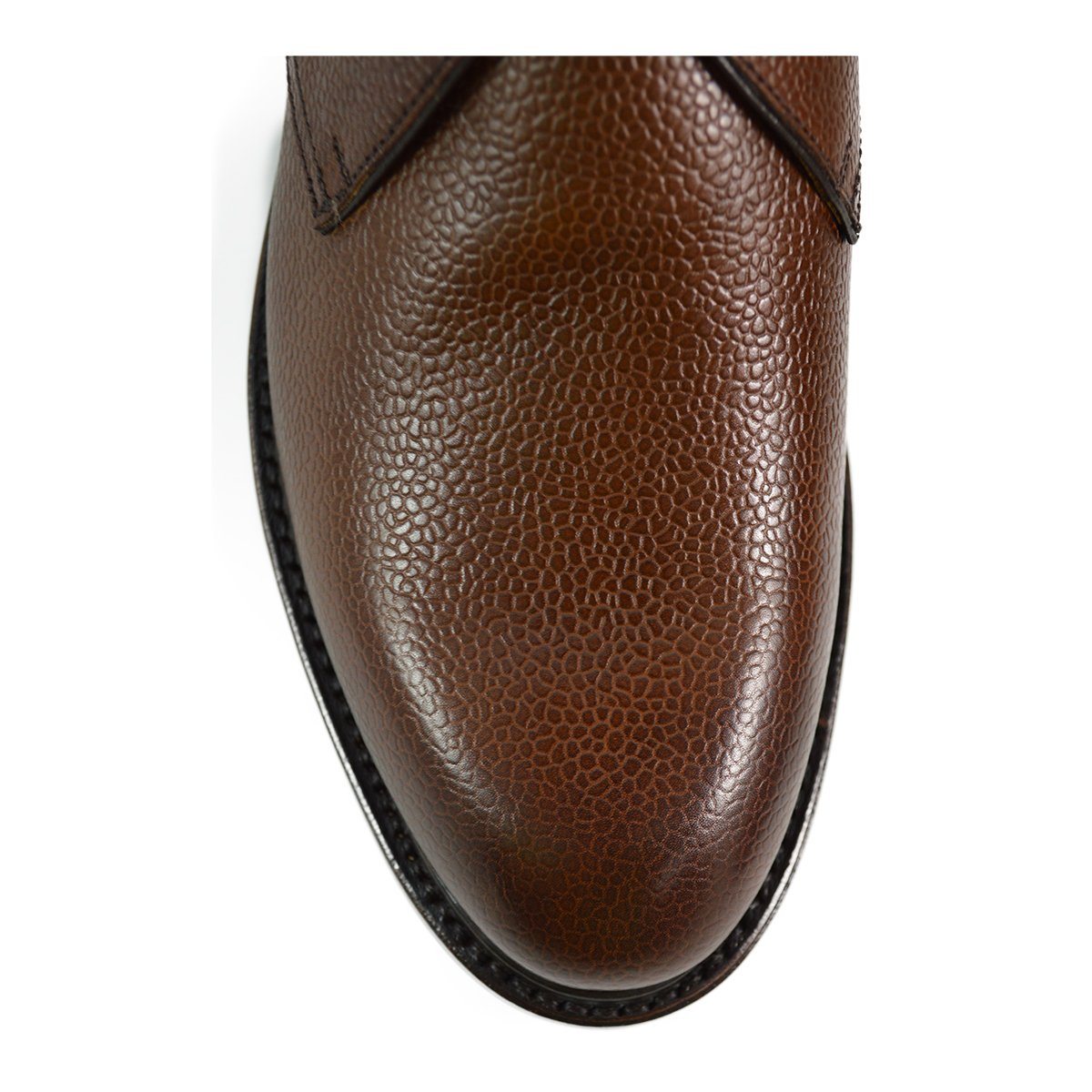 A dark brown grain leather chukka boot with a round toe and goodyear welted dainite rubber sole.
