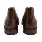 A dark brown grain leather chukka boot with a round toe and goodyear welted dainite rubber sole.
