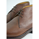 A dark brown grain leather chukka boot with a round toe and goodyear welted dainite rubber sole.