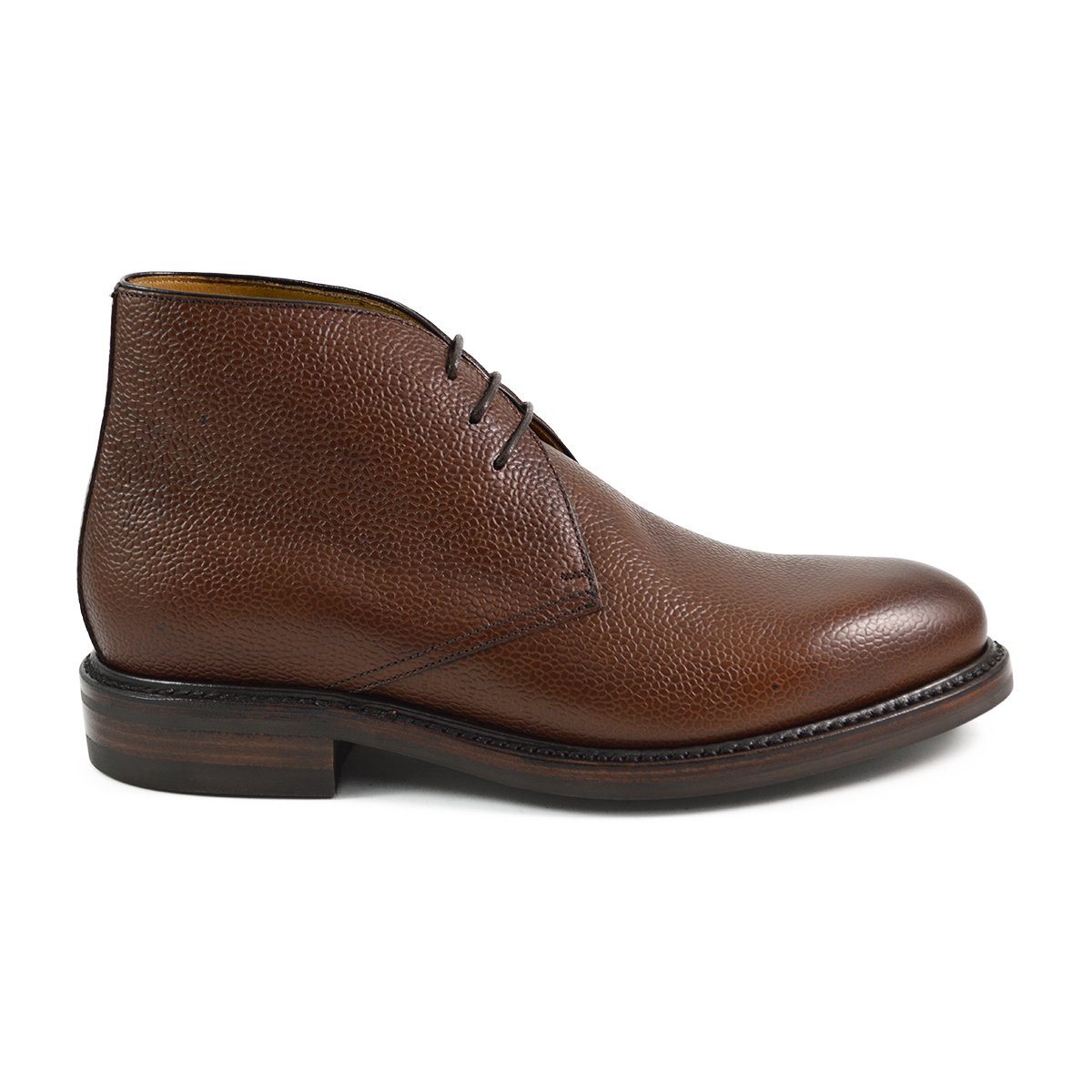 A dark brown grain leather chukka boot with a round toe and goodyear welted dainite rubber sole.