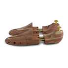 A pair of uncompressed cedar wood shoe trees with brass fitments, displayed in an open position.