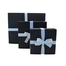 3 different sizes of black AFPOS gift boxes with white ribbon tired with a central bow