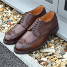 A Berwick 1707 brown brogue derby shoe with a round toe shape and lace-up closure. It features a grainy texture and brogue detailing & Dainite soles