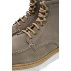 A grey and tan suede apron boot with lace-up closure, featuring a white sole and a natural welt.