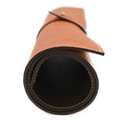 A Saphir Medaille D'Or rolled-up orange leather shoeshine mat with a nickel stud on the exterior.
