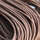 A close-up image of a waxed round brown shoe lace.