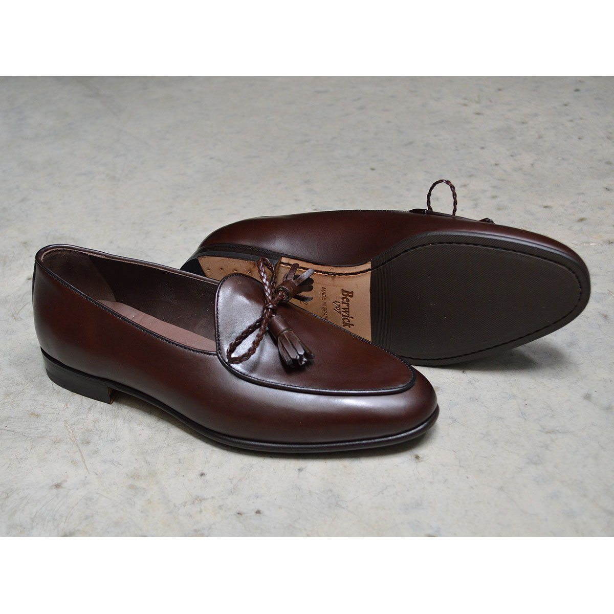 A Berwick 1 707 dark brown leather Belgian loafer with a braided leather bow tie and tassel adornment.