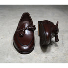 A Berwick 1 707 dark brown leather Belgian loafer with a braided leather bow tie and tassel adornment.