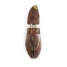 A pair of uncompressed cedar wood shoe trees with brass fitments, displayed in an open position.