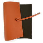 A Saphir Medaille D'Or rolled-up orange leather shoeshine mat with a nickel stud on the exterior.