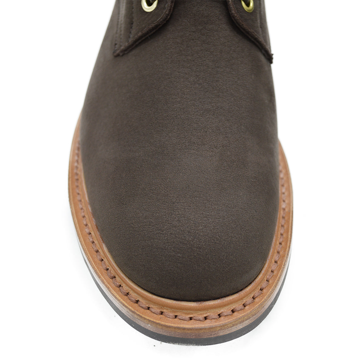 A dark brown Trickers Bernwood service boot made of Hydro Nubuck with a Dainite sole, featuring brass eyelets and a cream Barbour welt.