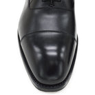 A black, boxcalf leather Oxford shoe with a chisel toe and lace-up closure, crafted in Spain.