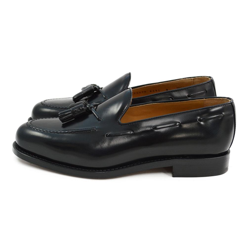 A black tasselled slip-on shoe with a high shine finish and a classic round toe.