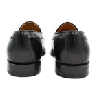 A black tasselled slip-on shoe with a high shine finish and a classic round toe.