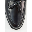 A black tasselled slip-on shoe with a high shine finish and a classic round toe.