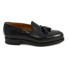 A black tasselled slip-on shoe with a polished, smooth upper and a classic round toe. The shoe is set against a white background.