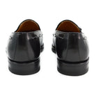 A black tasselled slip-on shoe with a polished, smooth upper and a classic round toe. The shoe is set against a white background.