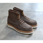 A grey and tan suede apron boot with lace-up closure, featuring a white sole and a natural welt.