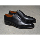 A black, boxcalf leather Oxford shoe with a chisel toe and lace-up closure, crafted in Spain.
