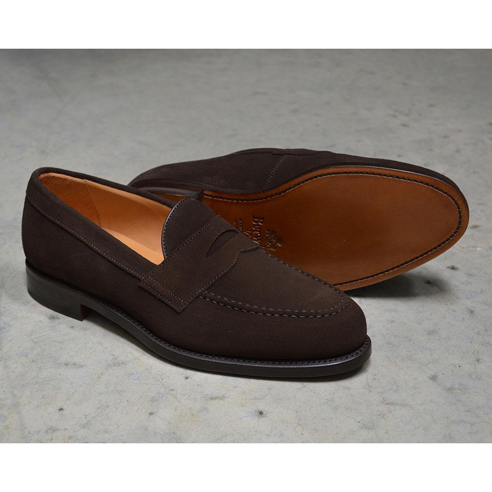 A dark brown suede penny loafer with a Goodyear welted leather sole, displayed on a polished concrete background.