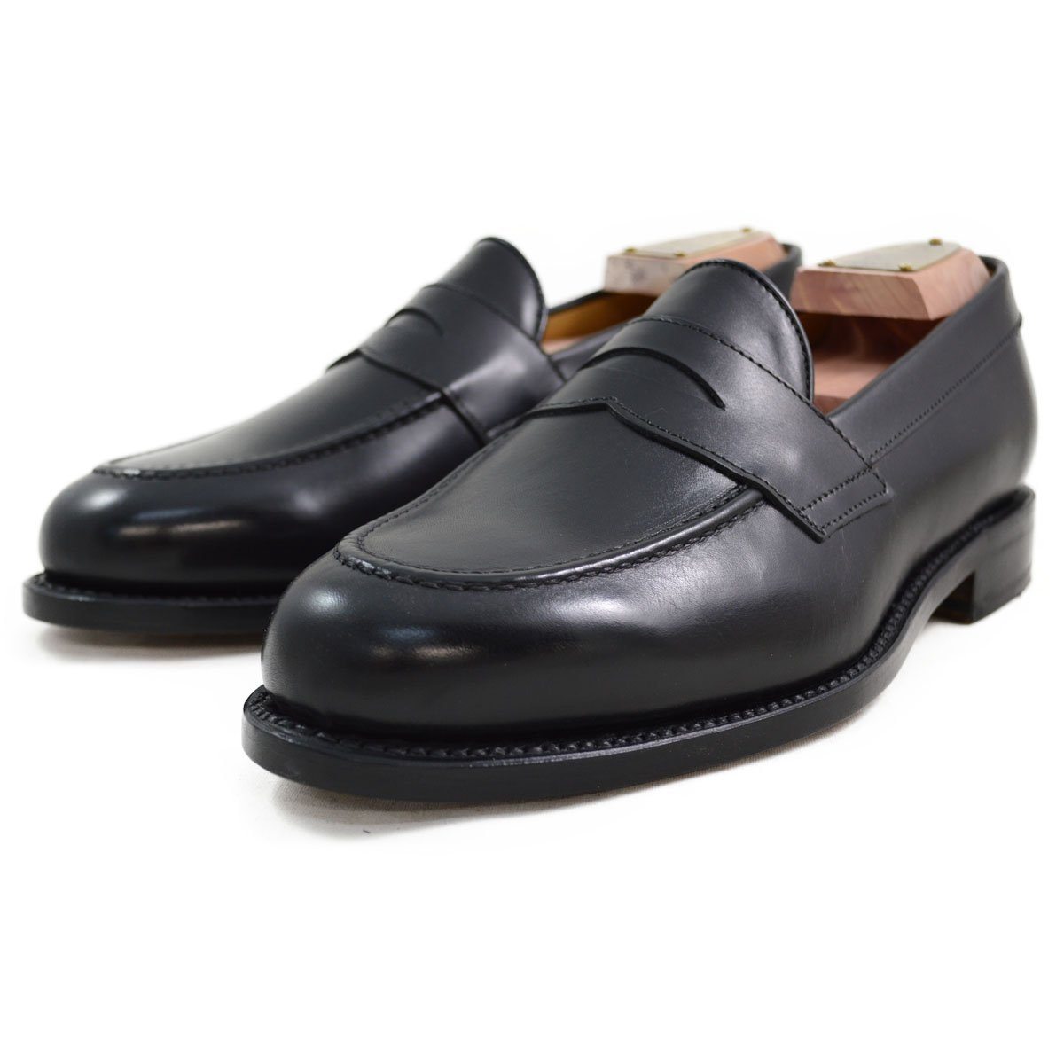 A classic black leather penny loafer shoe for men, with a closed vamp and a low heel.