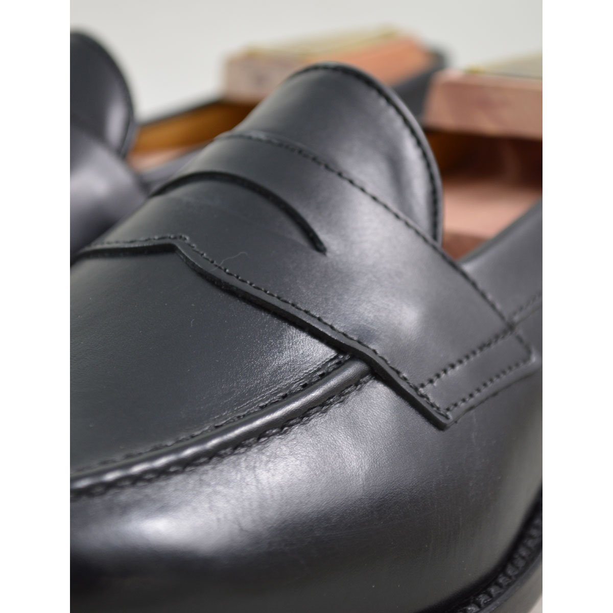A classic black leather penny loafer shoe for men, with a closed vamp and a low heel.