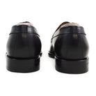 A classic black leather penny loafer shoe for men, with a closed vamp and a low heel.
