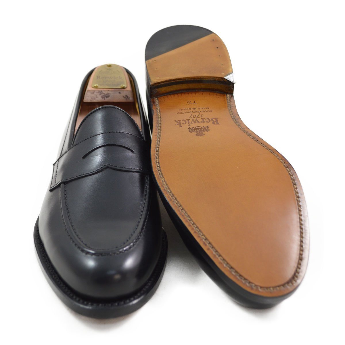 A classic black leather penny loafer shoe for men, with a closed vamp and a low heel.