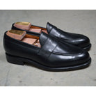 A classic black leather penny loafer shoe for men, with a closed vamp and a low heel.