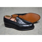 A classic black leather penny loafer shoe for men, with a closed vamp and a low heel.