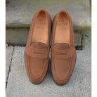 A brown suede penny loafer with a Dainite rubber sole, showing a classic round toe shape and a signature penny slot detail & Dainite Soles
