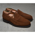 A brown suede penny loafer with a Dainite rubber sole, showing a classic round toe shape and a signature penny slot detail & Dainite Soles