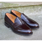 A dark brown Berwick 1707 Penny Loafer with a high-shine finish and a Dainite rubber sole.