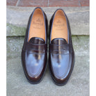 A dark brown Berwick 1707 Penny Loafer with a high-shine finish and a Dainite rubber sole.