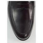 A burgundy high-shine leather penny loafer by Berwick 1707, displaying the classic round toe shape and the brand's distinctive penny slot detail.