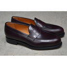 A burgundy high-shine leather penny loafer by Berwick 1707, displaying the classic round toe shape and the brand's distinctive penny slot detail.