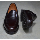 A dark brown Berwick 1707 Penny Loafer with a high-shine finish and a Dainite rubber sole.